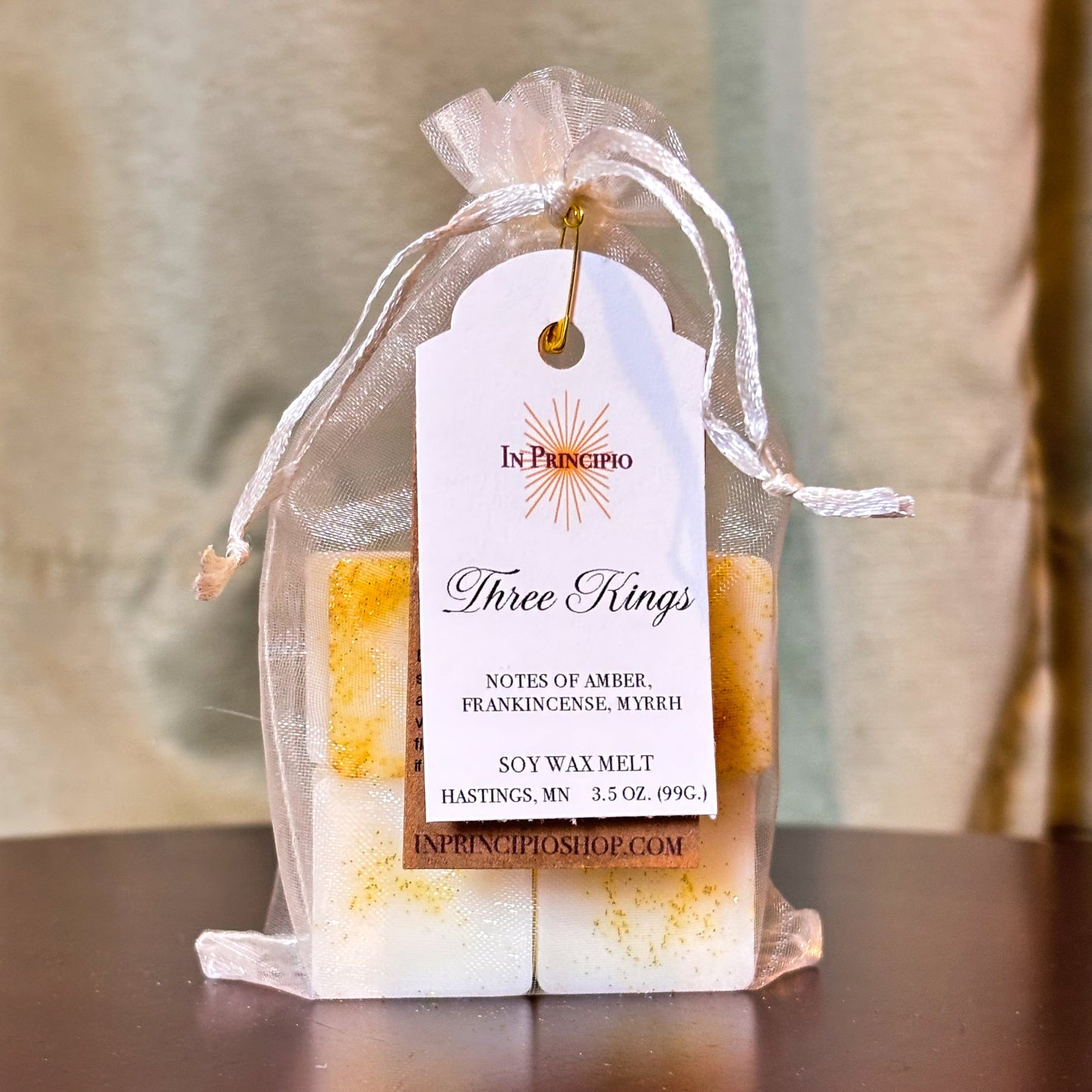 Soy wax melts in a decorative bag with a 'Three Kings' label on a wooden surface.