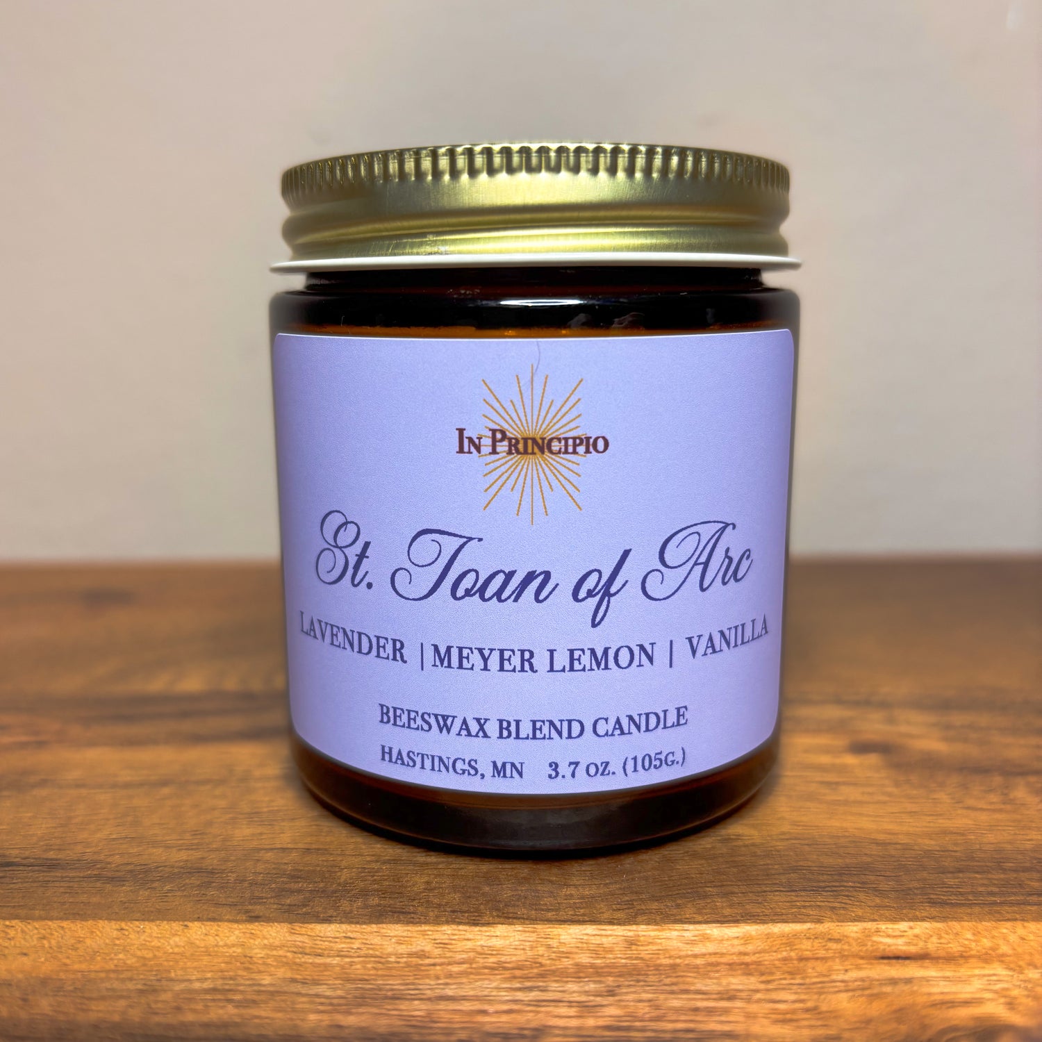 St. Joan of Arc mini 3.7 oz. scented container candle on a wooden surface
